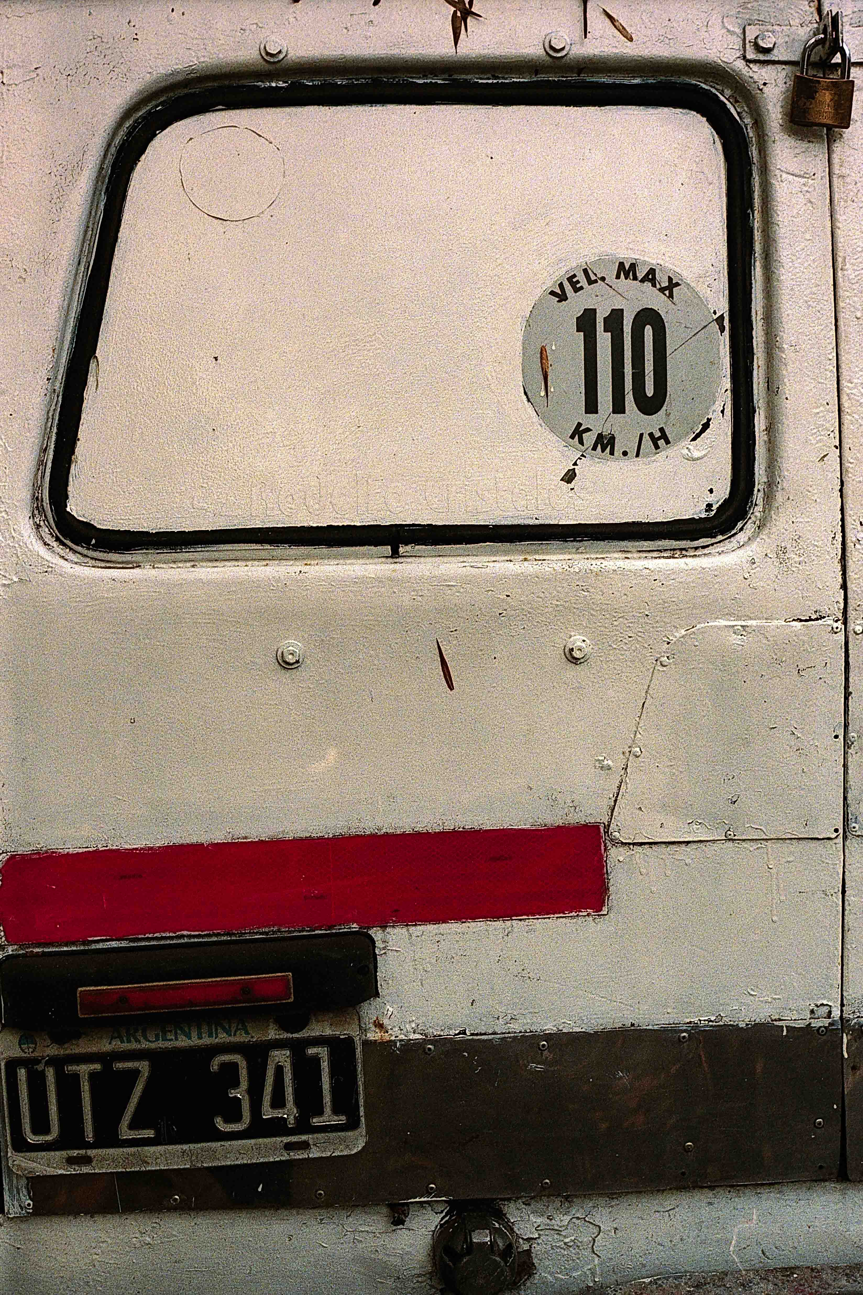 Puerta trasera de una furgoneta blanca con una franja roja y un círculo marcado 110.