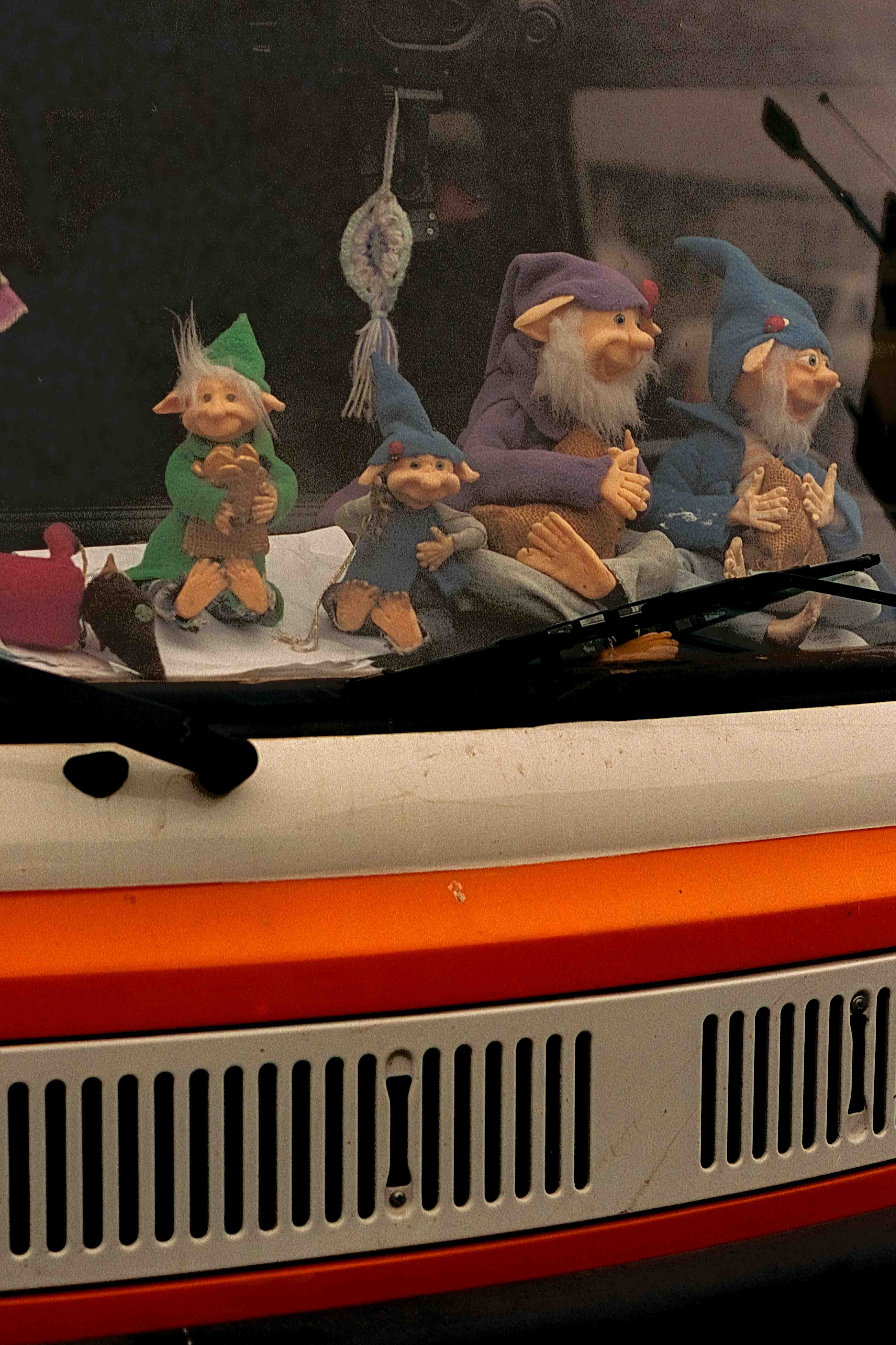 Fila de figuras de gnomos sobre el tablero de una furgoneta naranja y blanca.