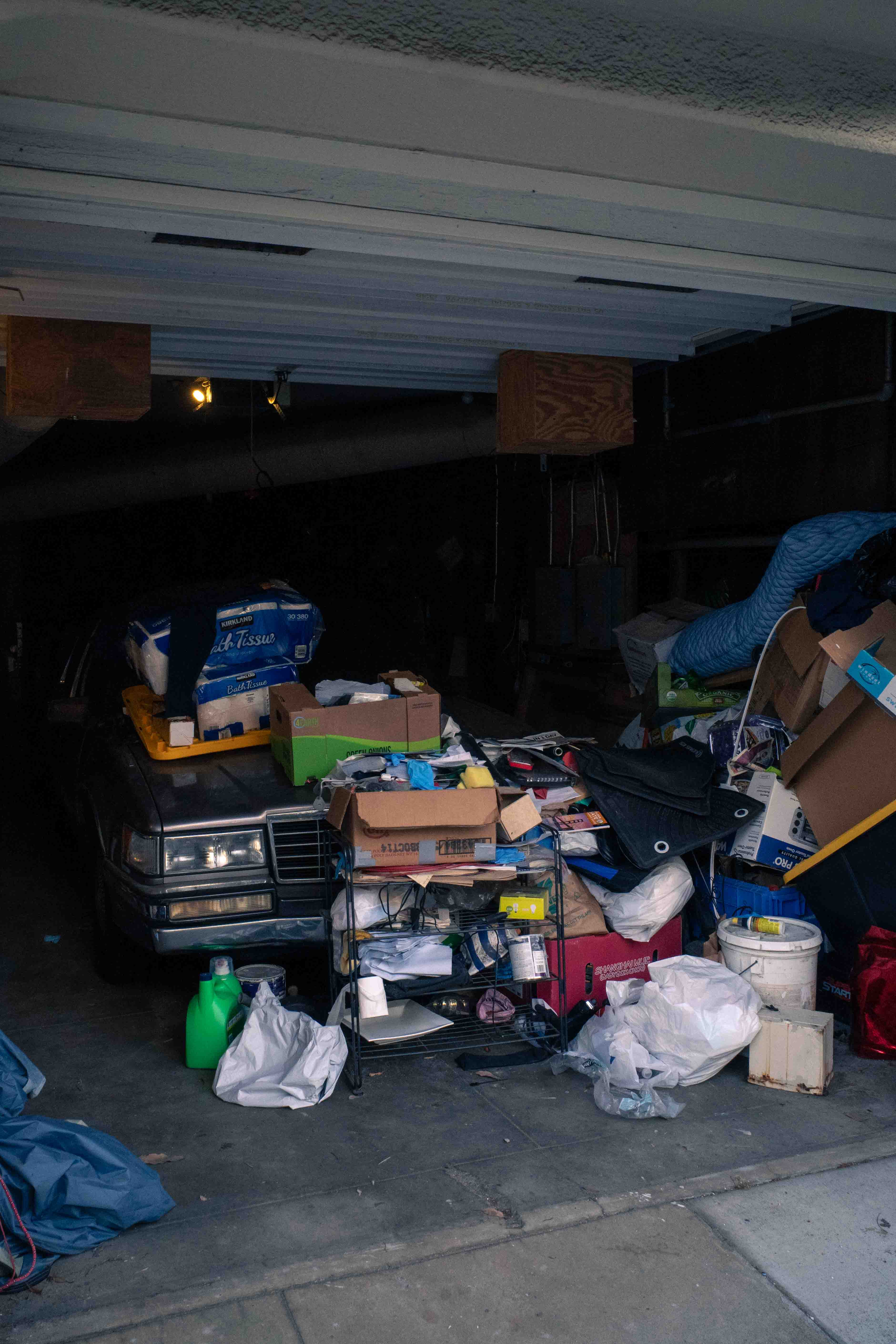 Cajas amontonados sobre un auto antiguo en un garage abierto