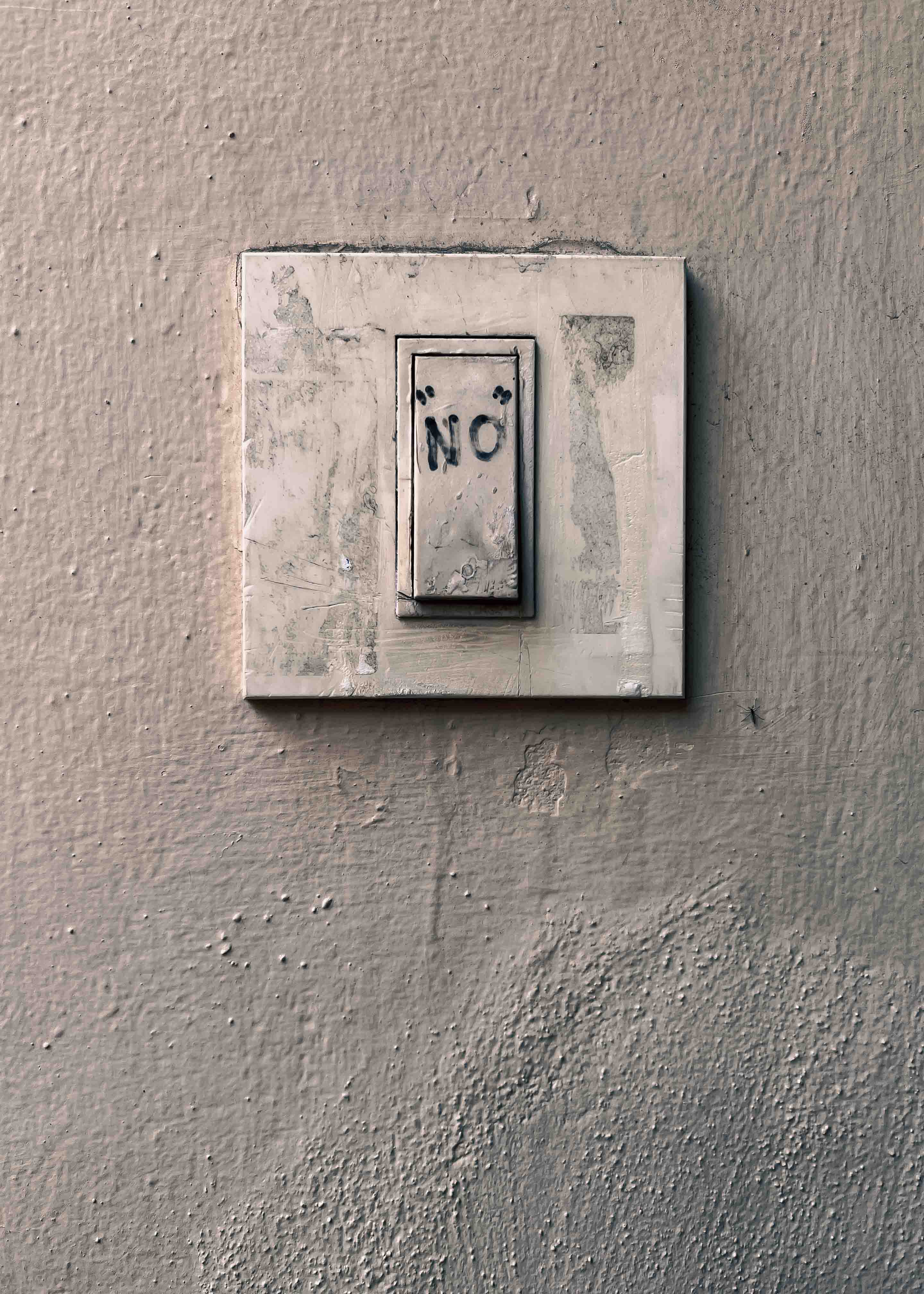 La palabra NO escrita dentro de un pequeño rectángulo enmarcado sobre una pared beige.