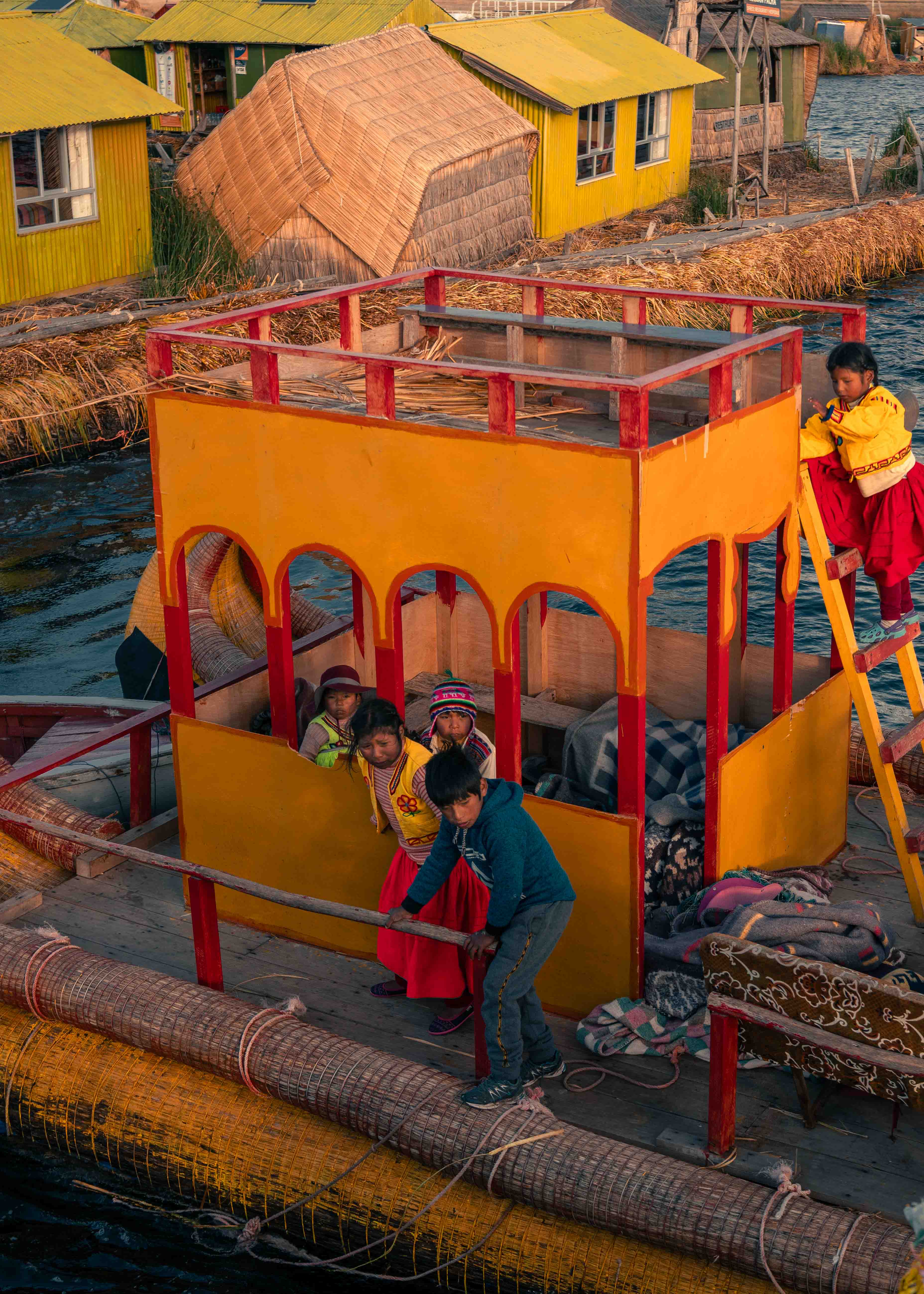 Personas junto a una cabina amarilla y roja sobre una embarcación de juncos, vista desde arriba.