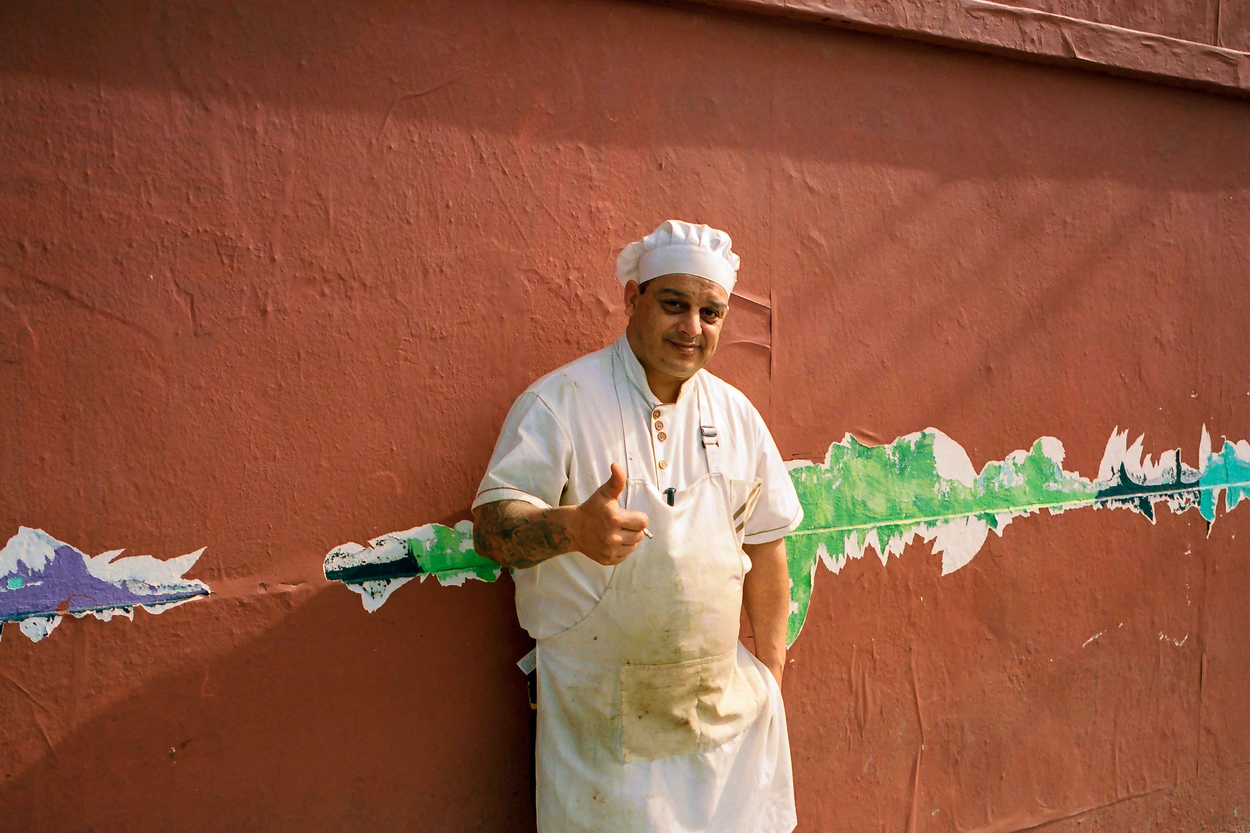 Retrato de un carnicero fumando un cigarrillo sobre una pared con rastros de papeles rotos