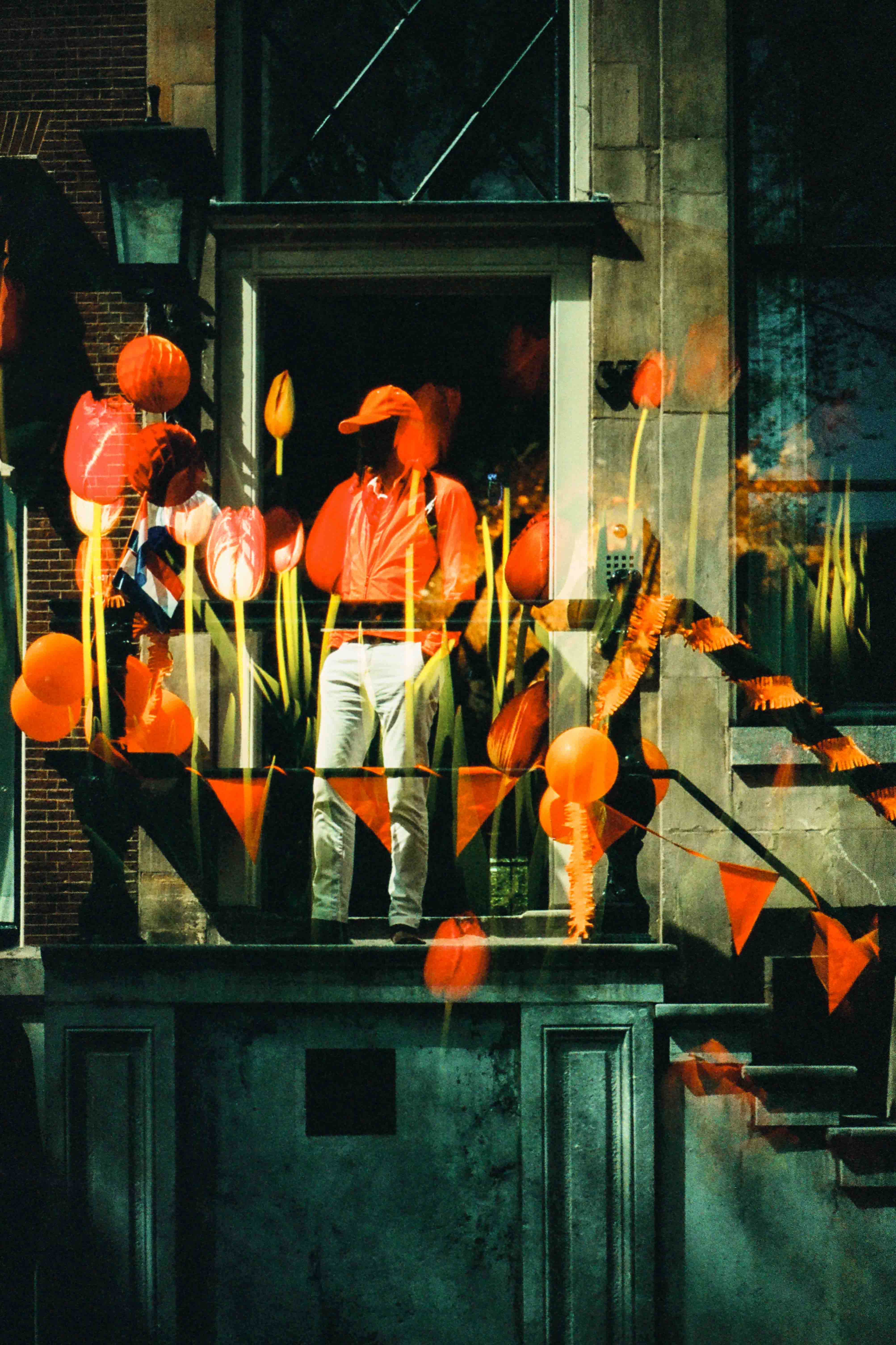 Personas en los escalones de una entrada decorada con globos y guirnaldas naranjas, con flores naranjas superpuestas.