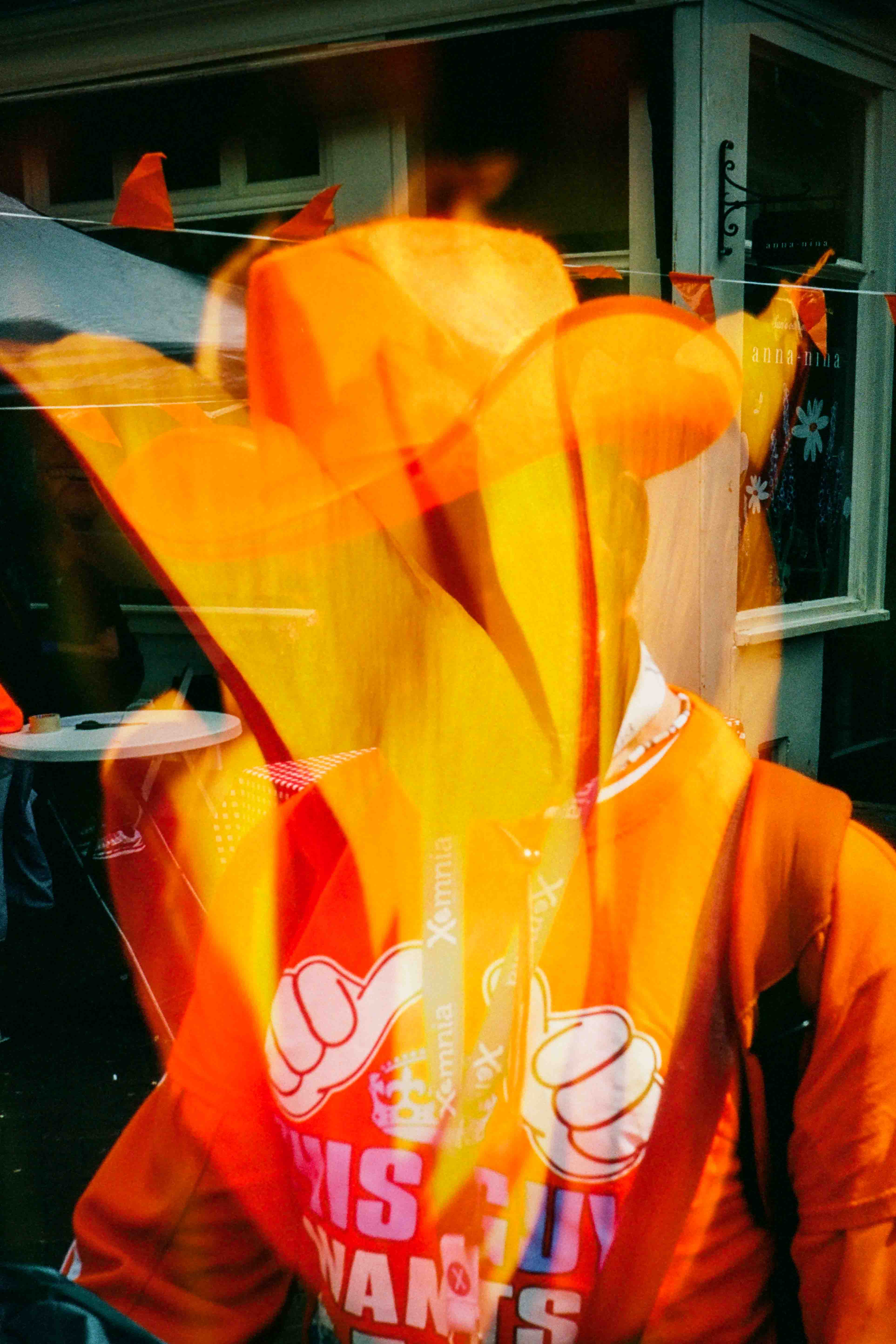 Persona con sombrero de vaquero y ropa naranja, con un gran tulipán naranja superpuesto sobre el rostro.
